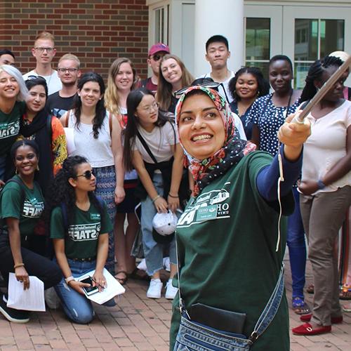 International students and faculty pose for a selfie in front of Baker University Center