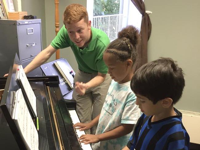 An Ohio University student gives a private piano lesson to young children